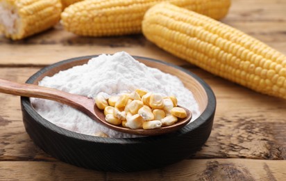 Photo of Bowl of corn starch and kernels on wooden table, closeup