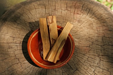 Photo of Palo santo sticks on wooden stump, top view