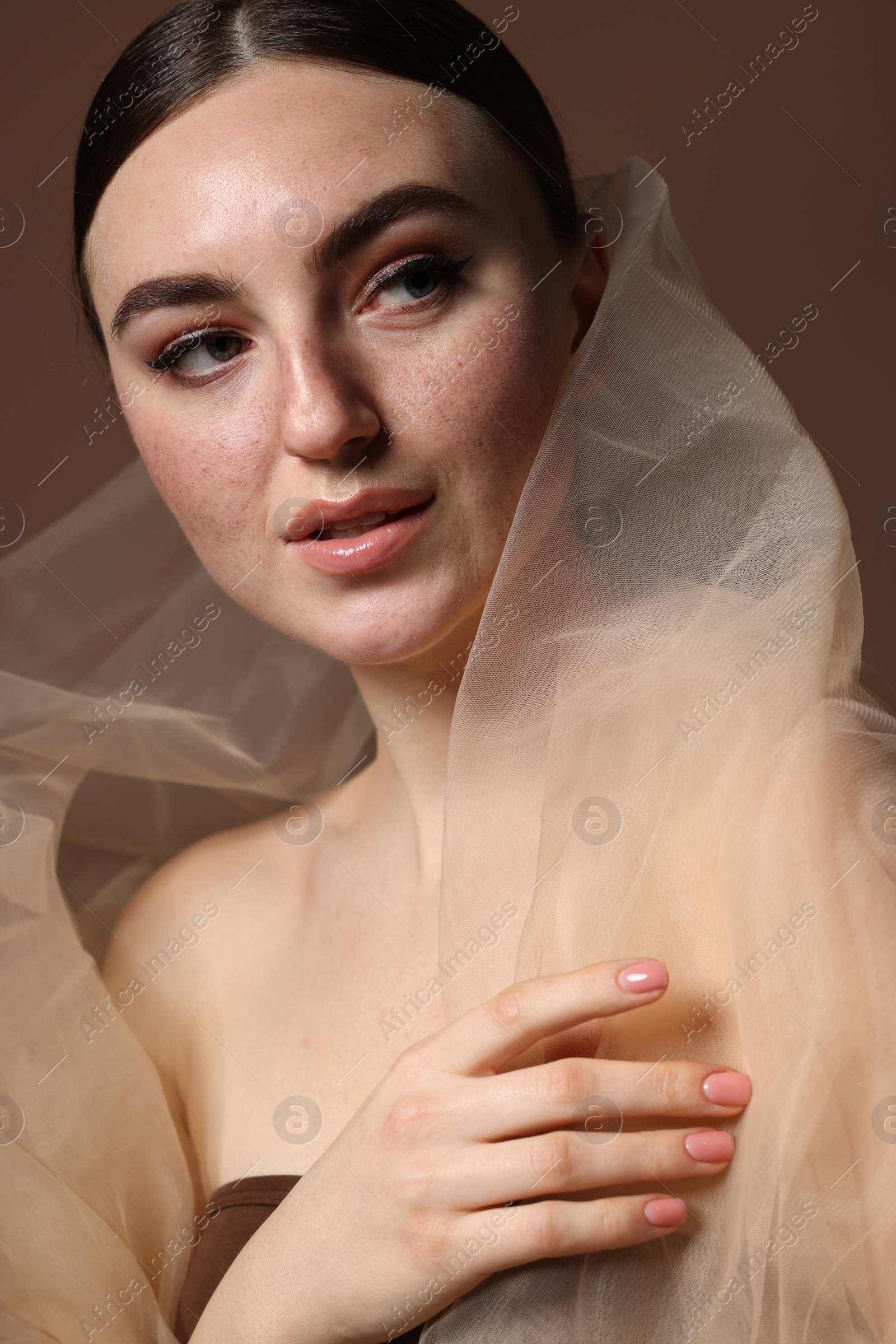 Photo of Fashionable portrait of beautiful woman with fake freckles on brown background