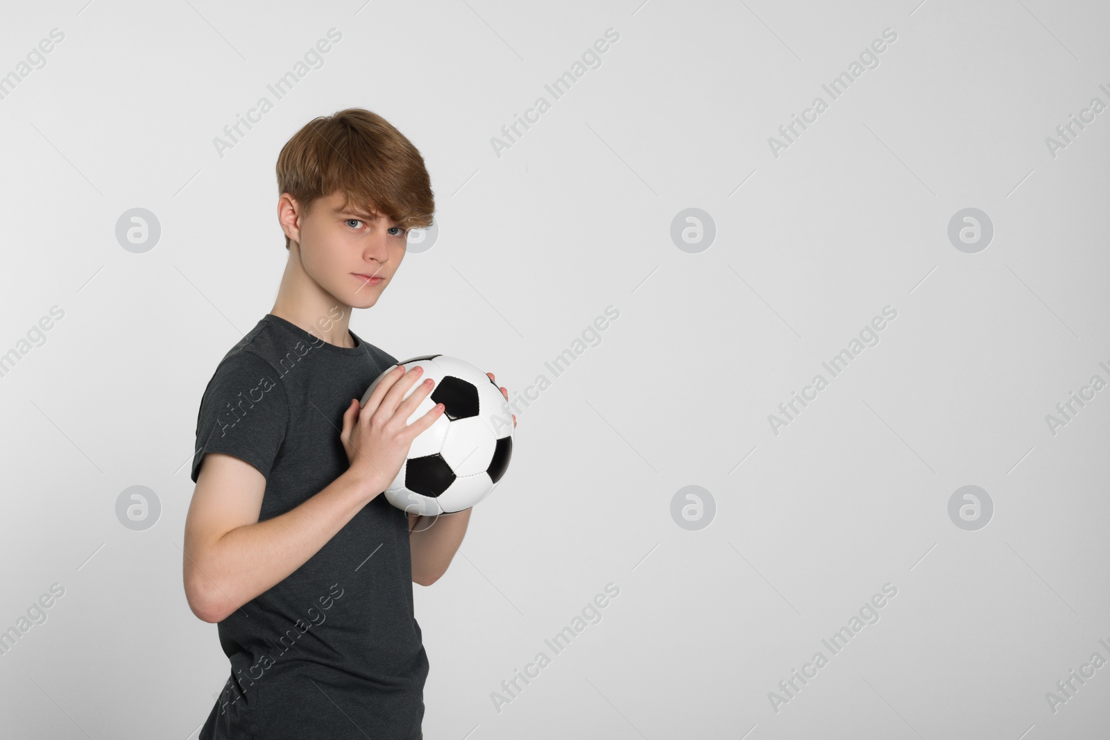 Photo of Teenage boy with soccer ball on light grey background. Space for text