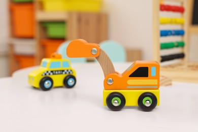 Photo of Cute wooden cars on table in kindergarten, closeup. Space for text
