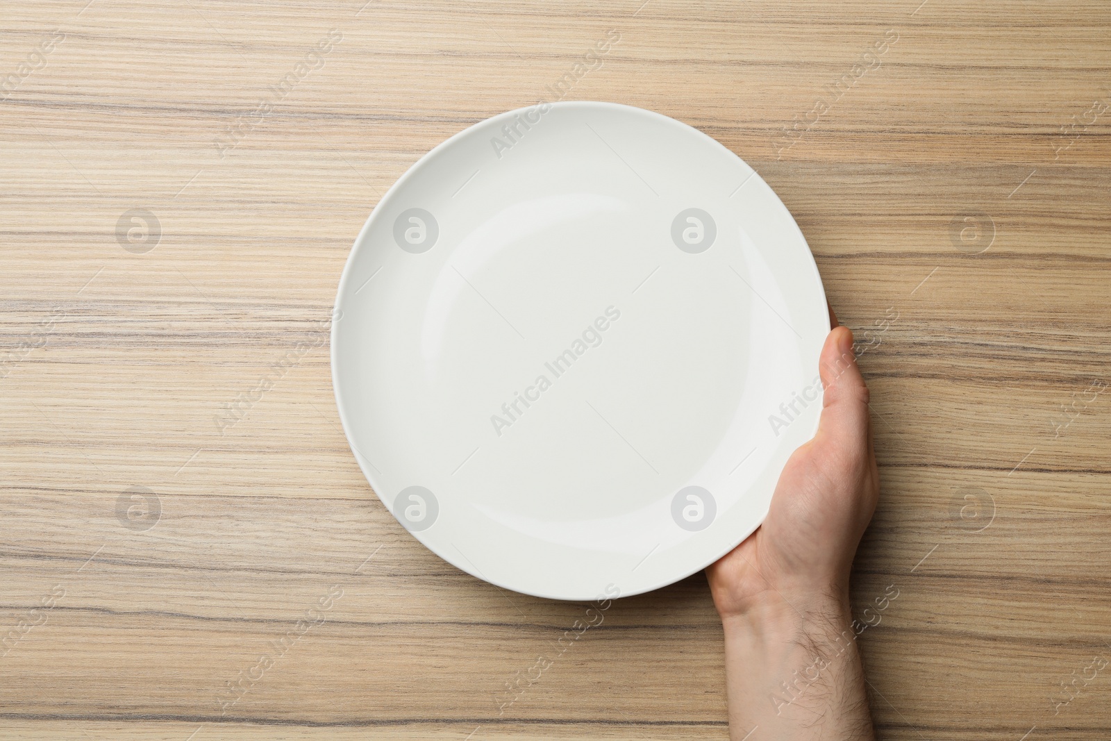 Photo of Man with empty plate at wooden table, top view