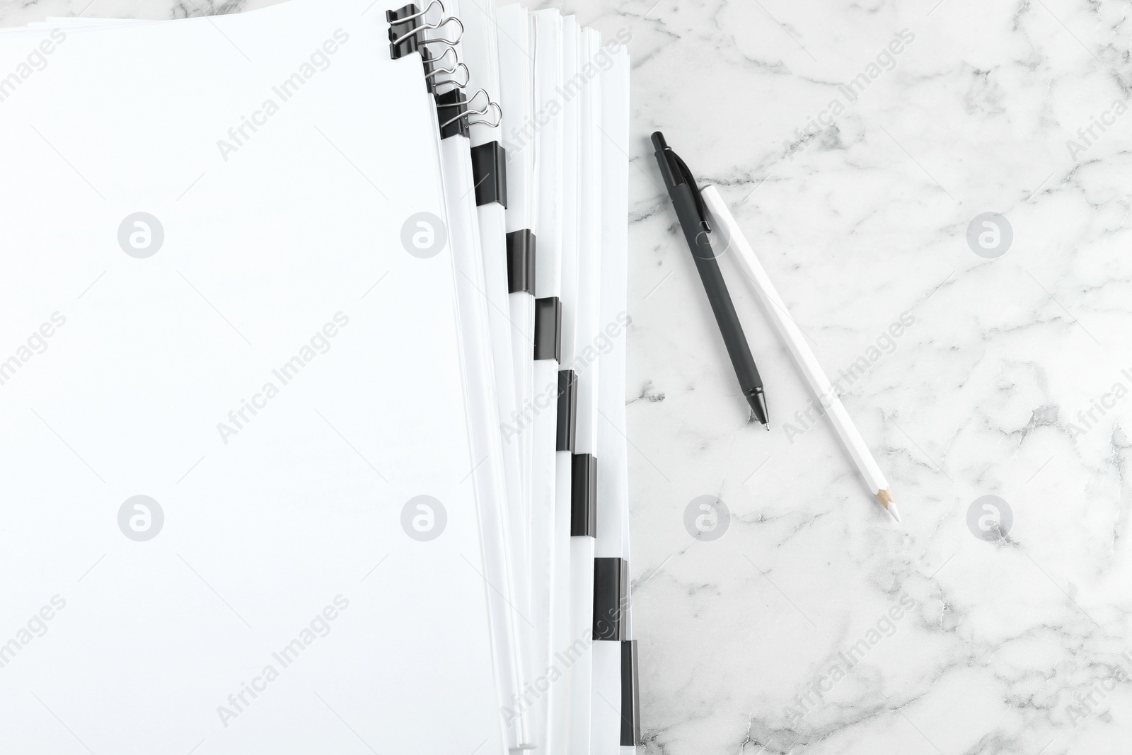 Photo of Stack of documents with binder clips on marble table, top view
