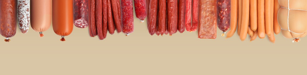 Image of Many different tasty sausages on beige background, flat lay. Banner design