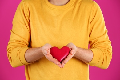 Man holding decorative heart on color background, closeup