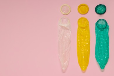 Unpacked condoms on pink background, flat lay with space for text. Safe sex