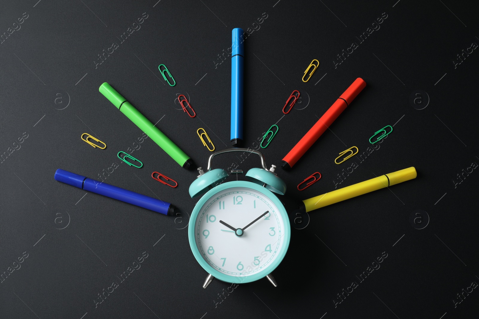 Photo of Flat lay composition with alarm clock and different stationery on black background. School time