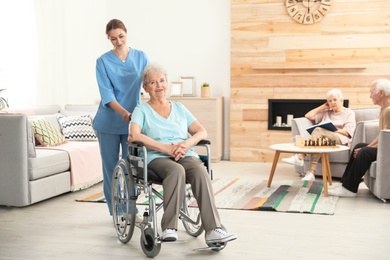 Nurse assisting elderly woman in wheelchair at retirement home. Space for text