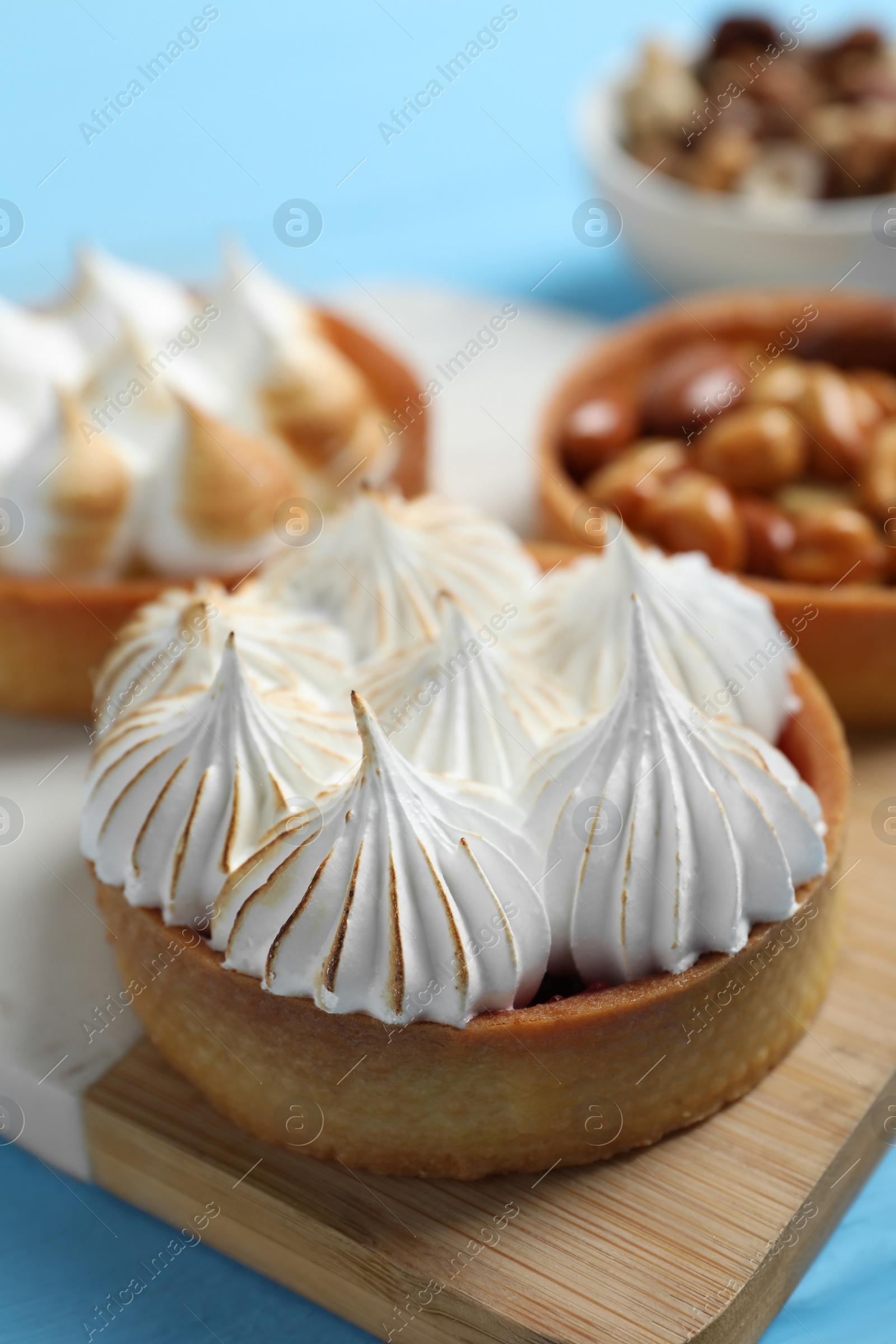 Photo of Different tartlets on light blue table, closeup. Delicious dessert