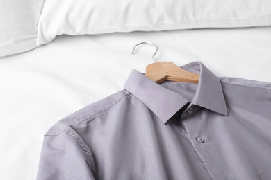 Stylish shirt on bed, closeup. Dry-cleaning service