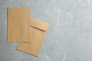 Kraft paper envelopes on grey marble background, flat lay. Space for text
