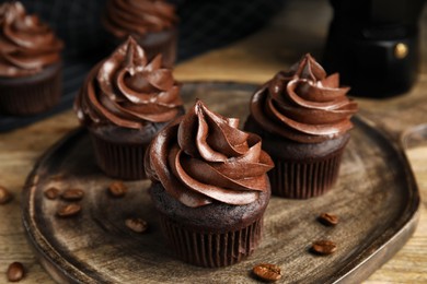Photo of Delicious chocolate cupcakes with cream on wooden table