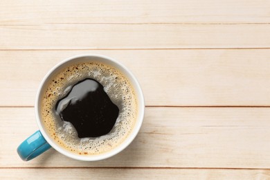 Cup of aromatic coffee on light wooden table, top view. Space for text