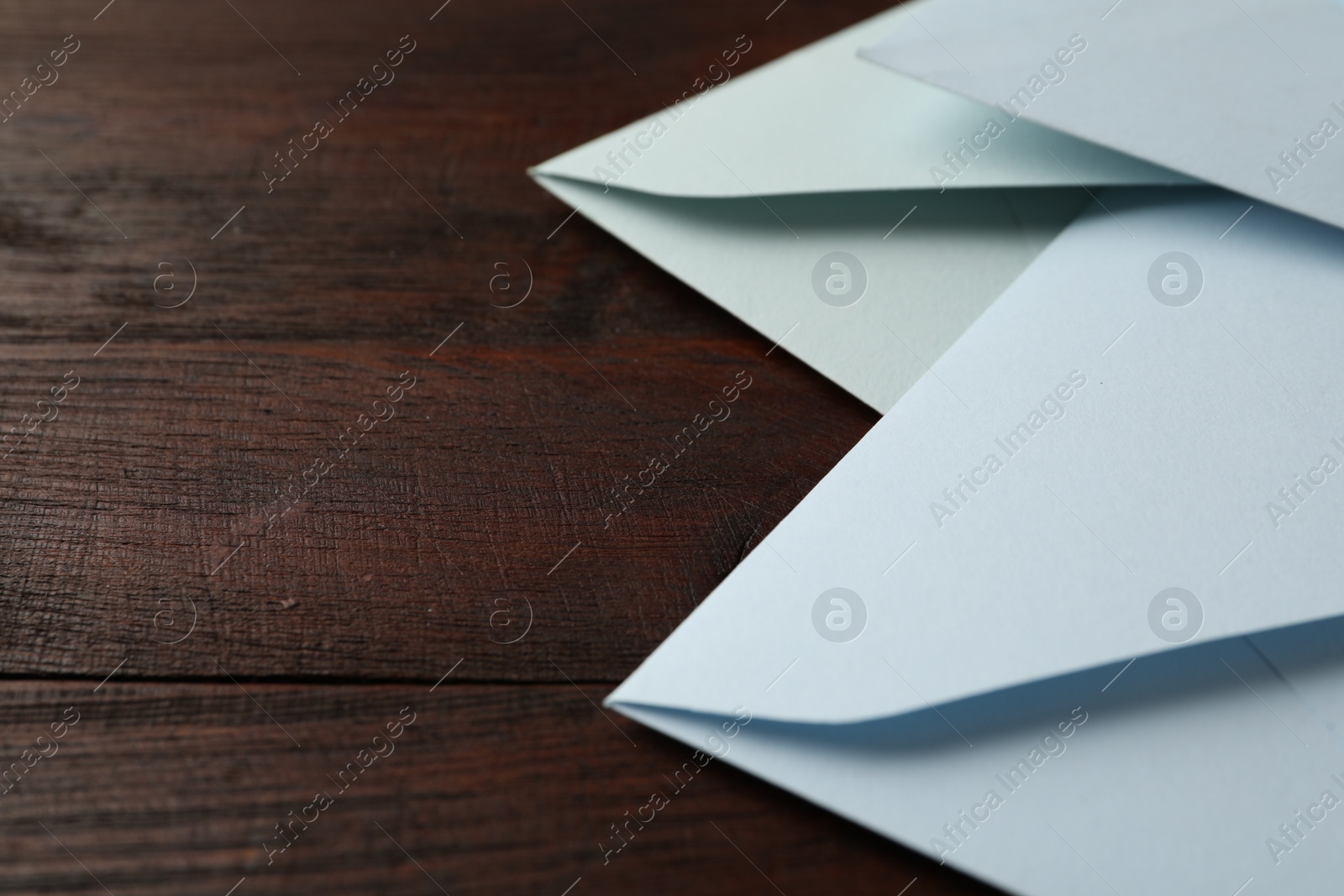 Photo of White paper envelopes on wooden table, closeup. Space for text