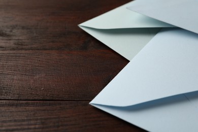 White paper envelopes on wooden table, closeup. Space for text