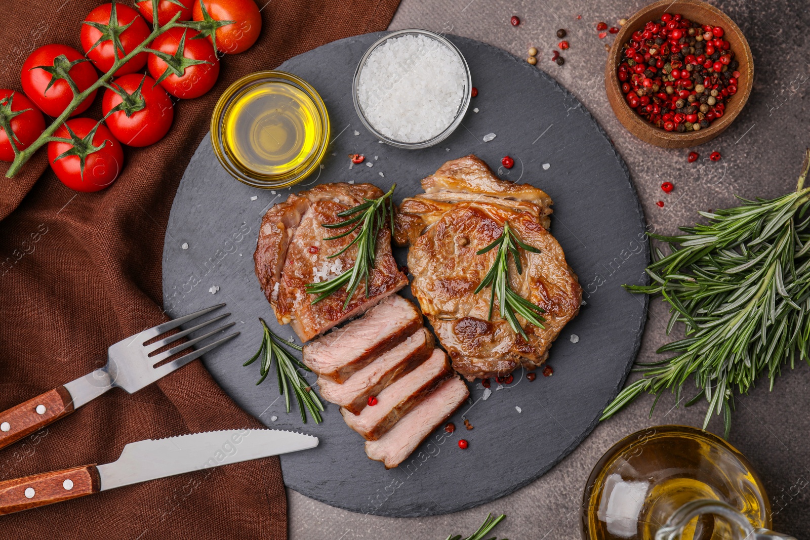 Photo of Pieces of delicious fried meat with rosemary served on brown table, flat lay