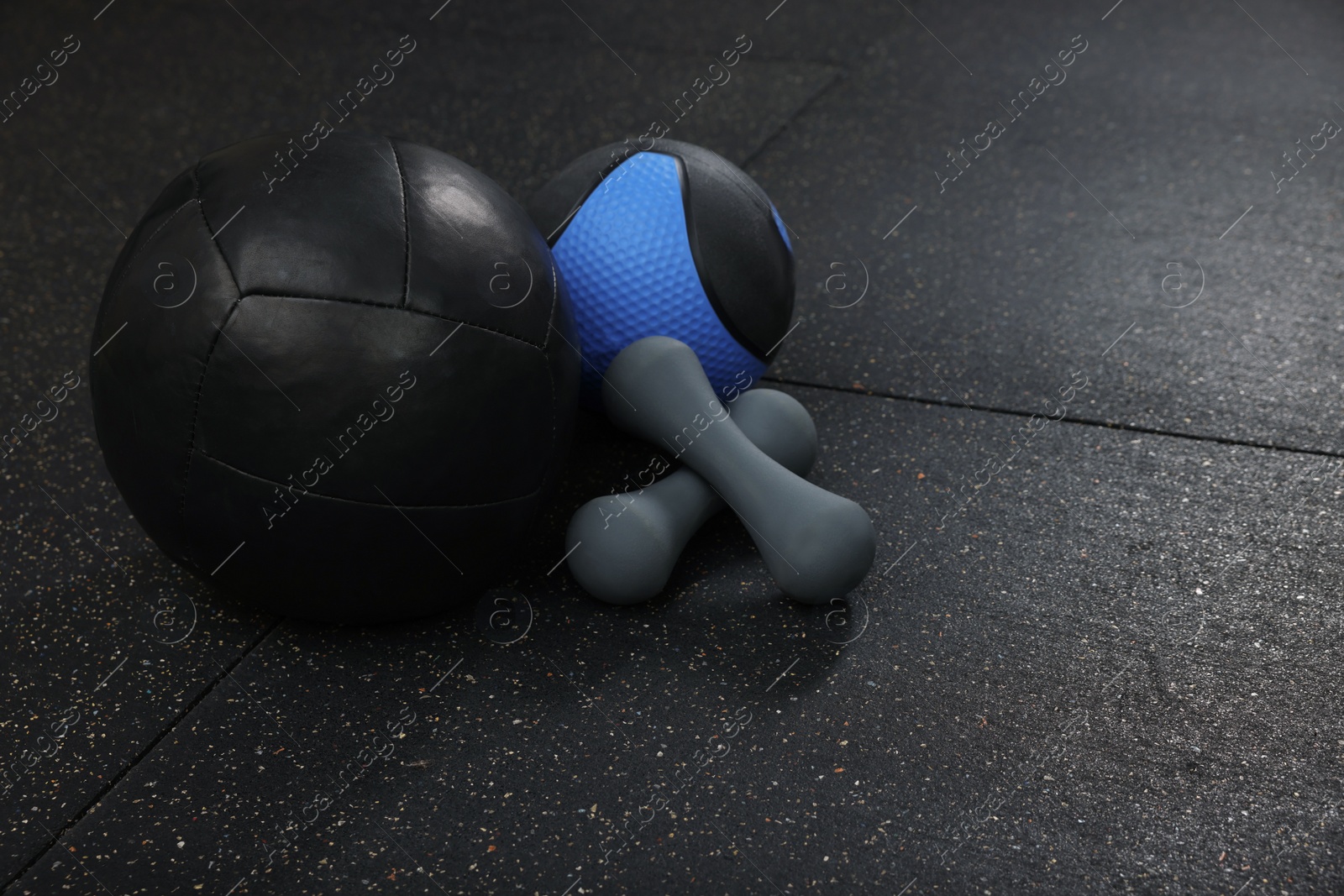 Photo of Medicine balls and dumbbells on black floor