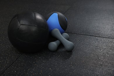 Medicine balls and dumbbells on black floor