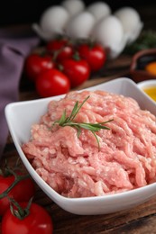 Photo of Raw chicken minced meat with rosemary on wooden table, closeup