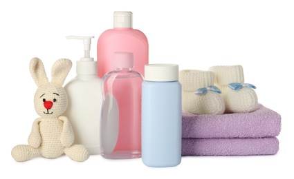 Bottles of baby cosmetic products, towels, toy bunny and booties on white background