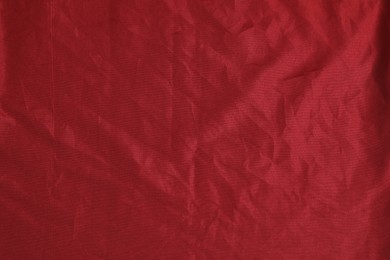 Photo of Crumpled dark red fabric as background, top view