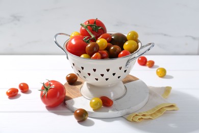 Photo of Metal colander with fresh tomatoes on white wooden table