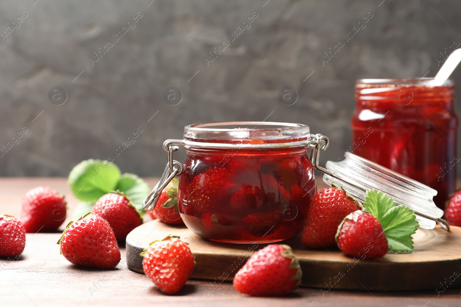 Photo of Delicious pickled strawberry jam and fresh berries on wooden table