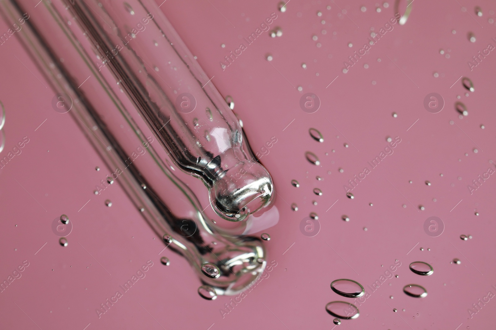 Photo of Pipette near serum drops on beautiful mirror, closeup with space for text. Toned in pink