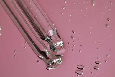 Pipette near serum drops on beautiful mirror, closeup with space for text. Toned in pink