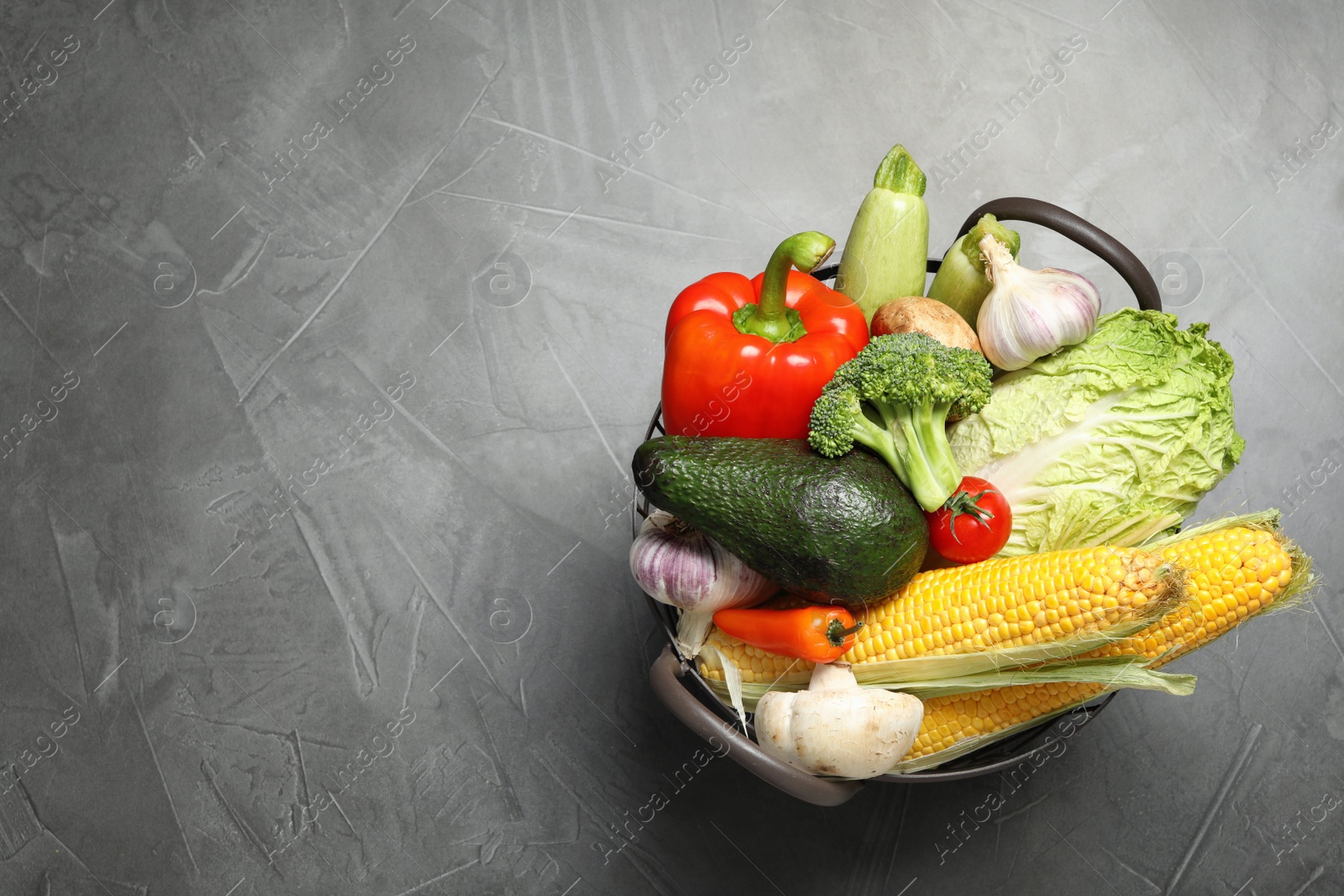 Photo of Basket with different fresh vegetables on grey background, top view. Space for text
