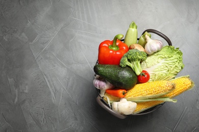 Basket with different fresh vegetables on grey background, top view. Space for text