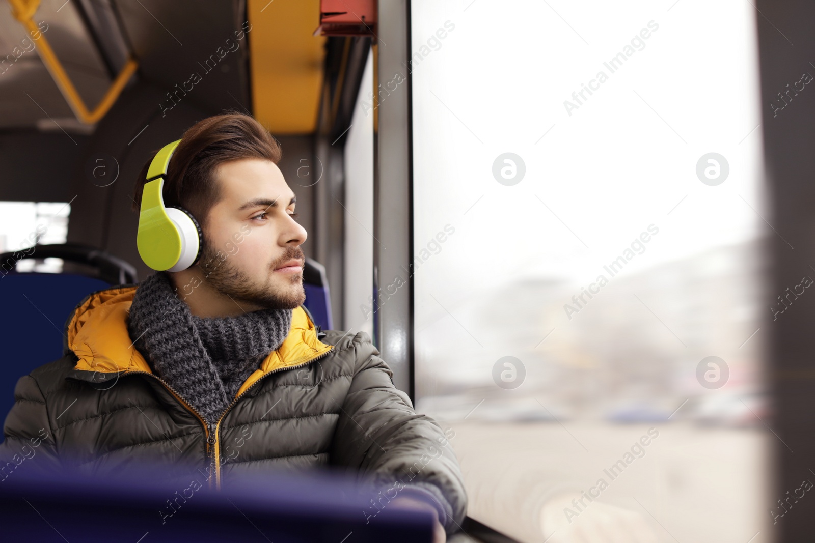 Photo of Young man listening to music with headphones in public transport