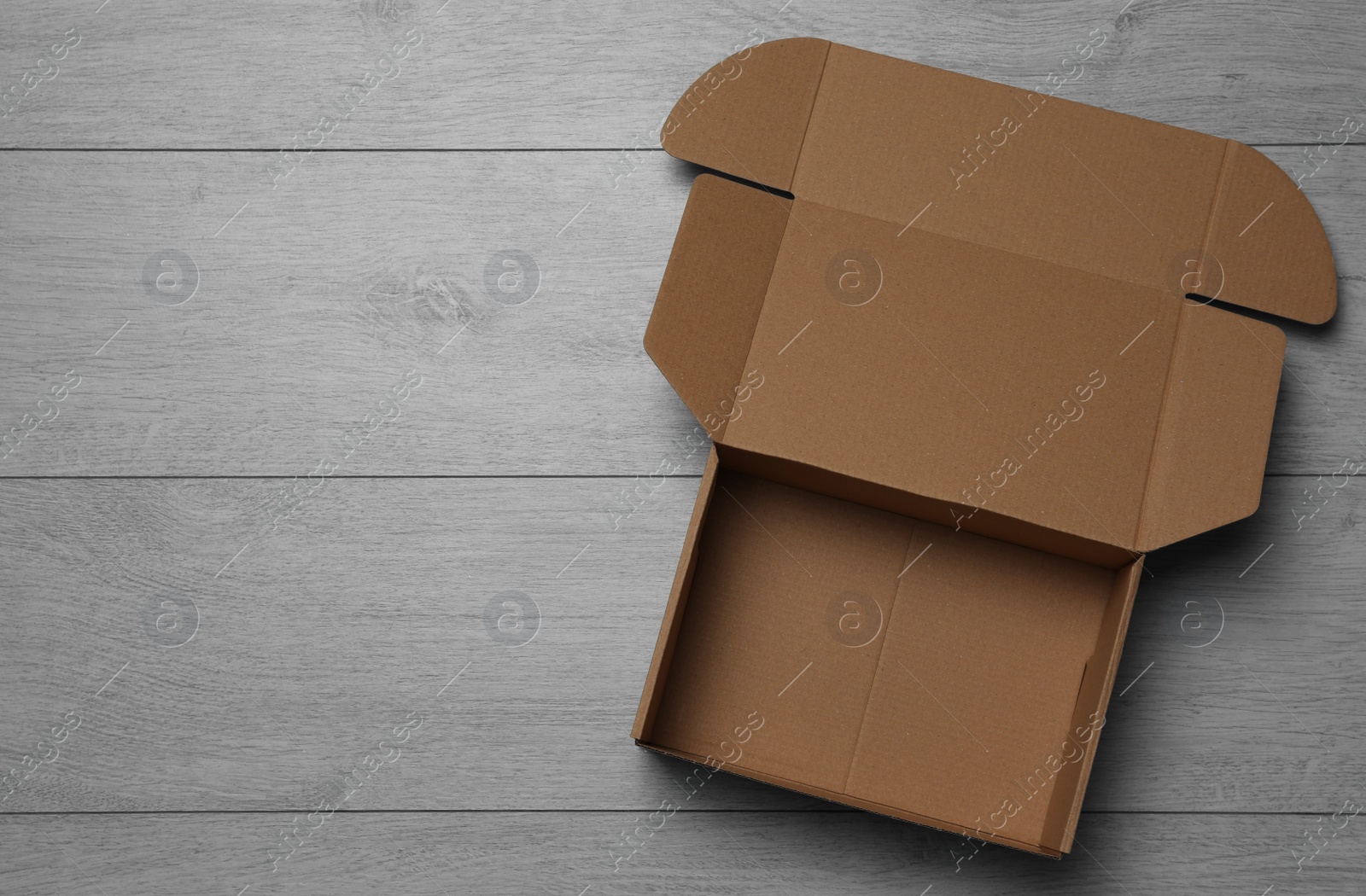 Photo of Empty open cardboard box on floor, top view. Space for text