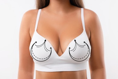 Breast surgery. Woman with markings on bra against white background, closeup