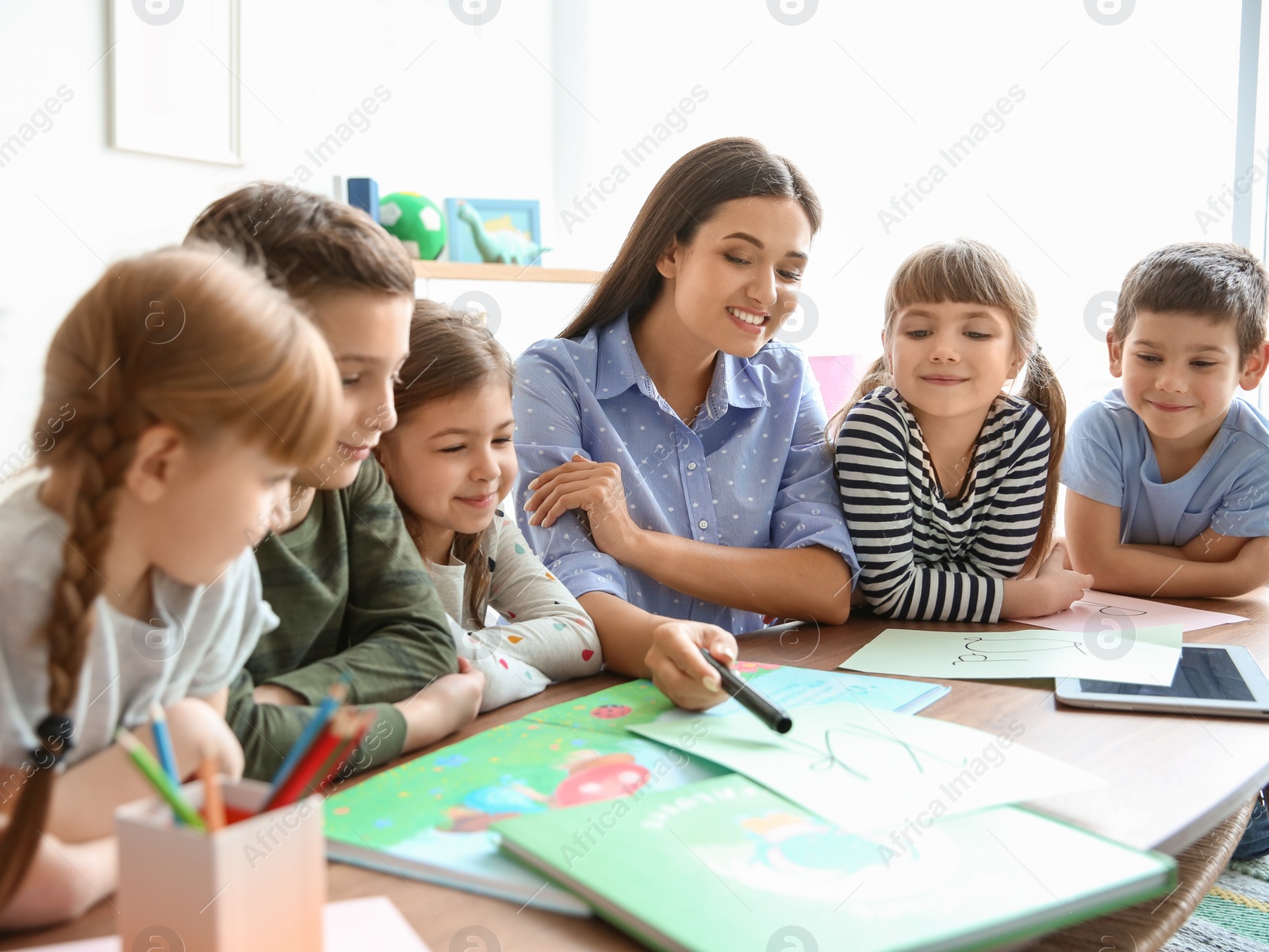 Photo of Cute little children with teacher in classroom at school