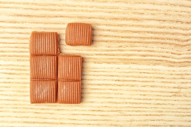 Photo of Delicious caramel candies on wooden background, top view