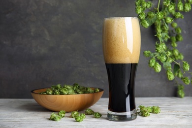 Composition with tasty beer and fresh green hops on wooden table. Space for text