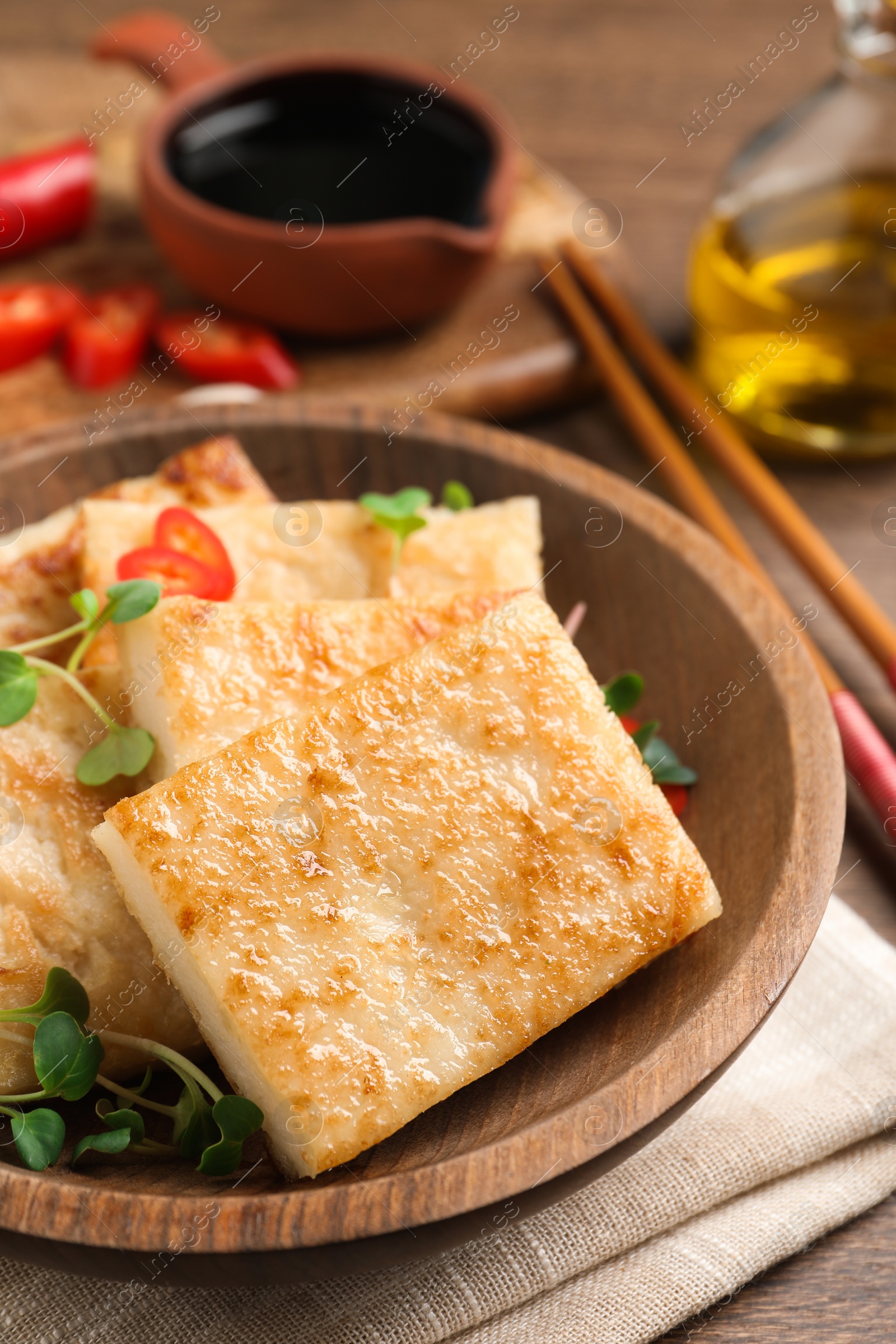 Photo of Delicious turnip cake with microgreens on wooden table, closeup