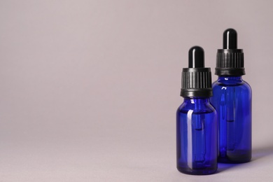 Photo of Cosmetic bottles of essential oils on color background. Space for text