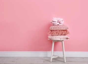 Photo of Many different pillows on chair near color wall with space for text