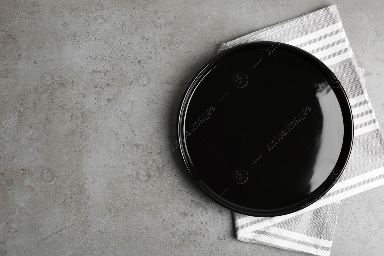 Photo of Empty plate and napkin on grey table, top view. Space for text