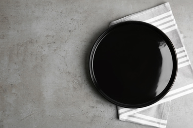 Photo of Empty plate and napkin on grey table, top view. Space for text