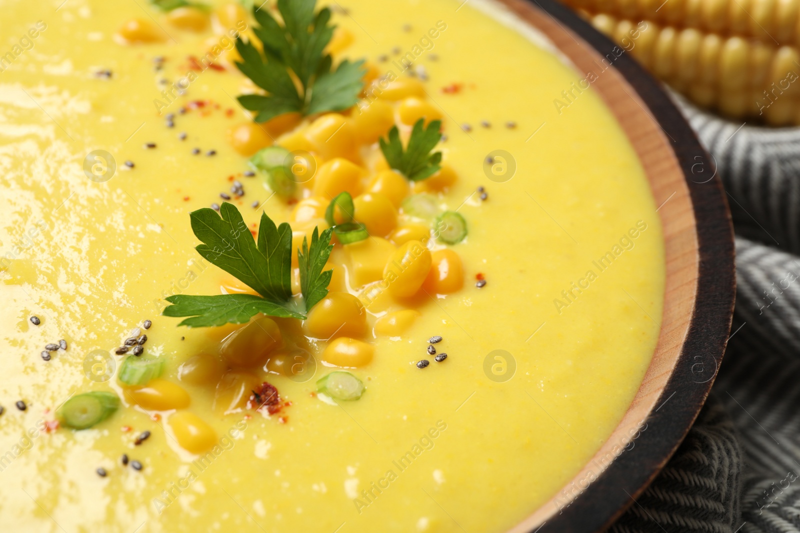 Photo of Delicious creamy corn soup in wooden bowl, closeup