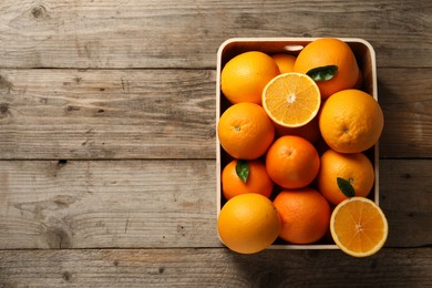 Many whole and cut ripe oranges on wooden table, top view. Space for text