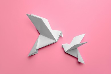 Photo of Beautiful origami birds on pink background, flat lay