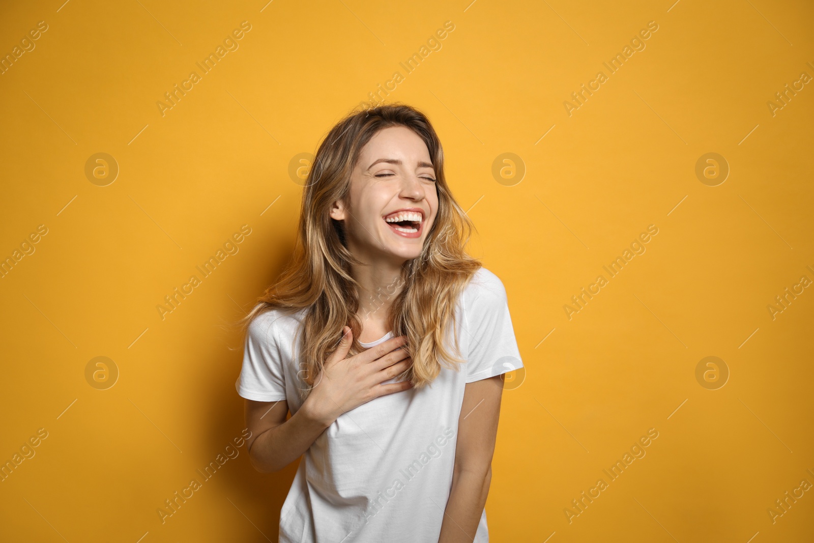 Photo of Cheerful young woman laughing on yellow background