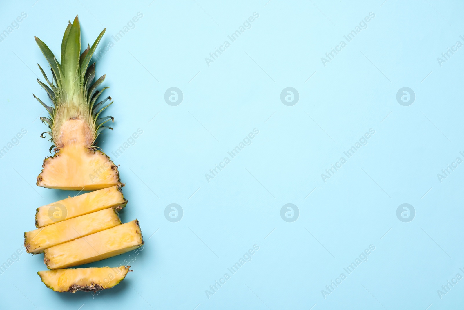 Photo of Cut fresh pineapple on light blue background, top view. Space for text