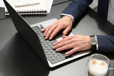 Woman working on laptop at black desk in office, closeup