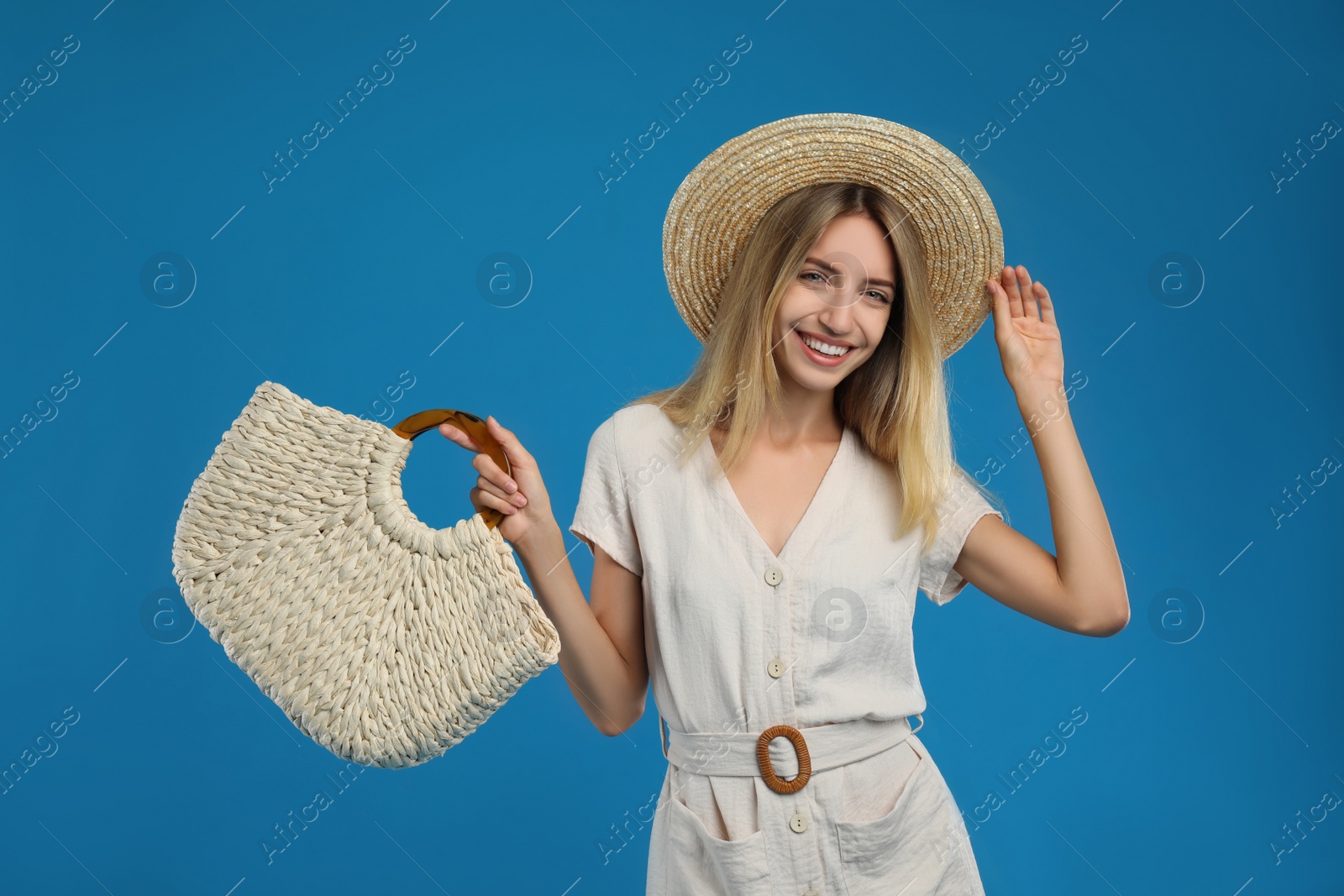 Photo of Beautiful young woman with stylish straw bag on blue background