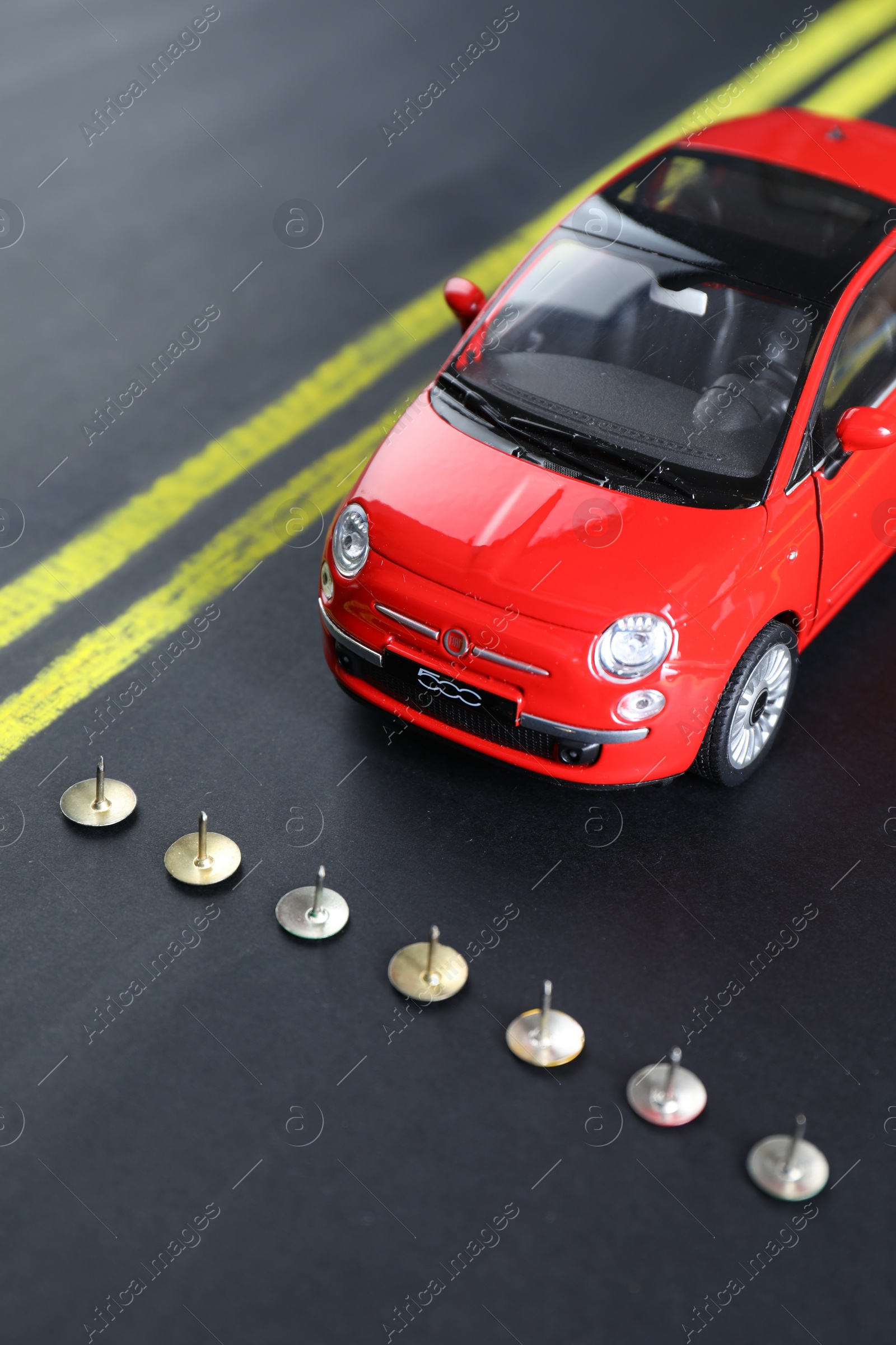 Photo of Pins as barrier blocking way for red toy car. Development through obstacles overcoming
